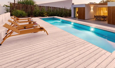 Des bains de soleil sur une terrasse en bois devant une piscine