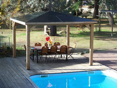 Une pergola abrite un salon de jardin devant une piscine
