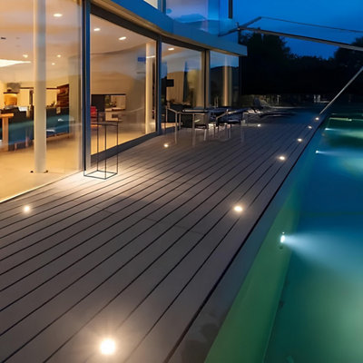 Une terrasse de piscine en bois avec des spots encastrés