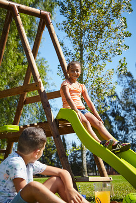 Fille descendant toboggan et garçon assis au sol