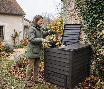 Remplissage d'un composteur de jardin avec feuilles mortes et déchets organiques en novembre en France. Travaux d'automne au potager.