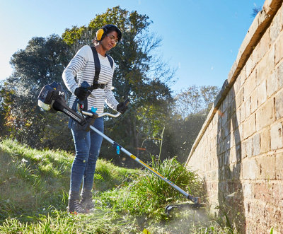Illustration d'une femme équipée d'un harnais pour débroussailler le long d'un mur