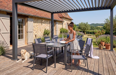 Un jeune fille met la table sous une pergola bioclimatique