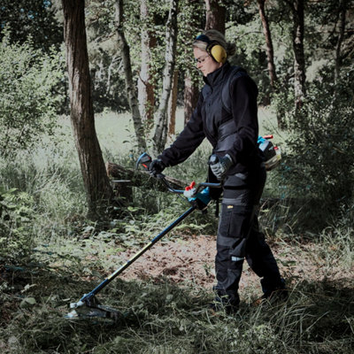 Un homme passe la débrousailleuse dans un sous-bois