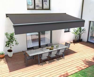 Store banne mural noir protégeant du soleil un salon de jardin blanc sur terrasse bois