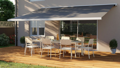 Grand store banne motorisé ouvert sur table de jardin blanche