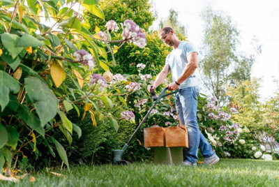 Dans un jardin, un homme taille avec un coupe-bordures