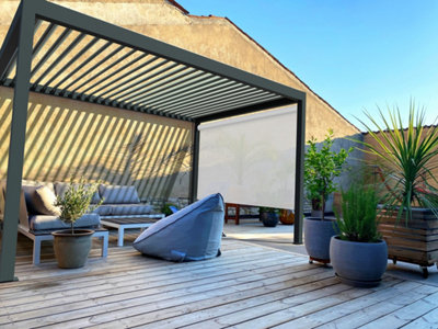 Une pergola bioclimatique sur une terrasse en bois adossée à une maison