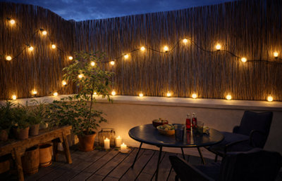 Une clôture de jardin avec une guilande lumineuse