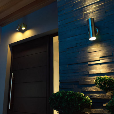 Une porte d'entrée éclairée avec 2 types d'appliques