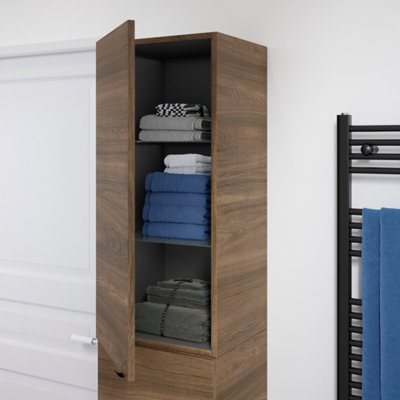 Meuble colonne en bois foncé entre-ouvert sur des accessoires de salle de bain