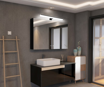 salle de bain avec un miroir et un spot lumineux au-dessus d'un lavabo blanc sur mur gris.