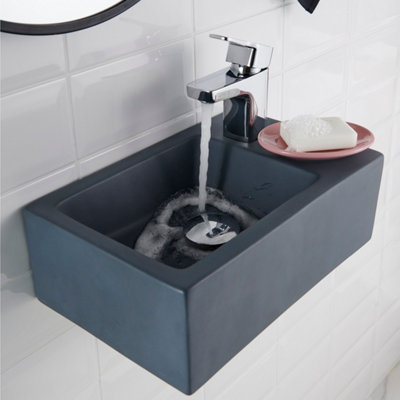Lave-mains suspendu foncé avec robinet ouvert