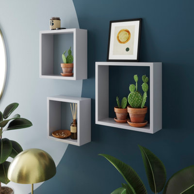 étagère cube blanche sur mur blanc et plantes à l'intérieur.