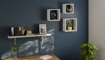 3 cubes et 1 tablette murale blanc sur mur bleu foncé avec déco