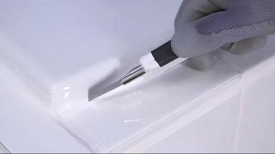 Un cutter enlève le joint silicone de la baignoire