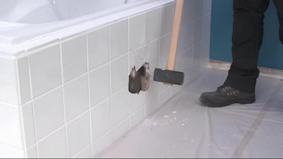 Avec une masse, casse du carrelage sur le tablier