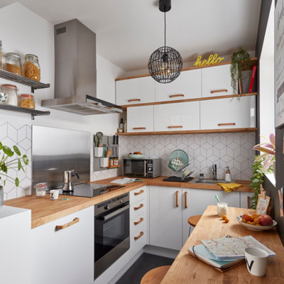 Petite cuisine avec des rangements optimisés sur toute la hauteur et un plan snack sous une fenêtre.