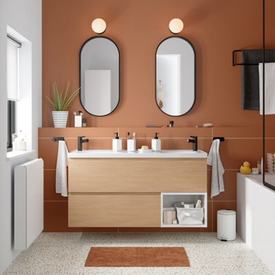 salle de bain terracotta, un meuble vasque en bois et des miroirs ovales.