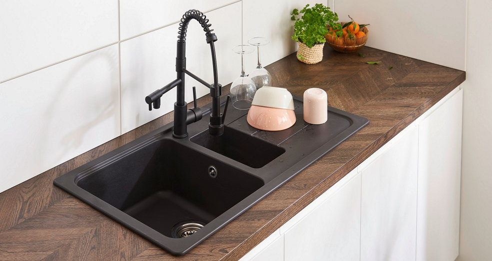 Un bel évier encastré de couleur anthracite sur un plan de travail imitant bois