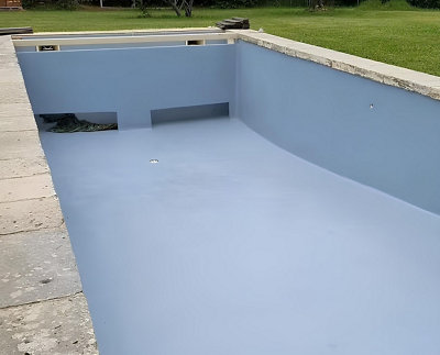 Une piscine en béton peint en bleu clair