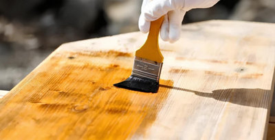 Passage d"une couche d'huile sur une table de jardin en bois exotique