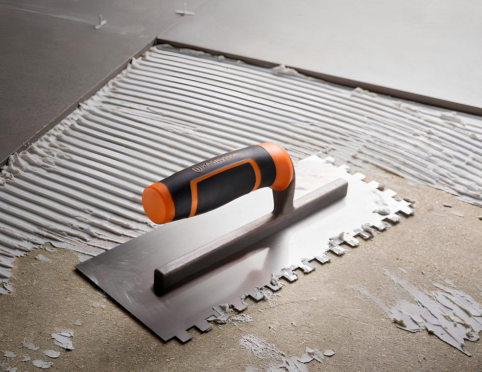 Un chantier de pose de carrelage avec un platoir à colle