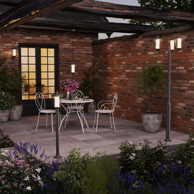 Une terrasse de nuit éclairée par des appliques, une borne et un lampadaire extérieur