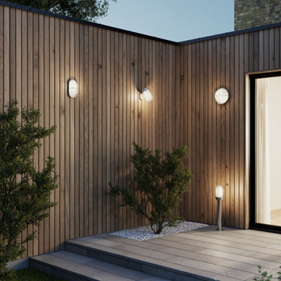 le murs d'une maison jouxtant une terrasse avec des appliques et une borne