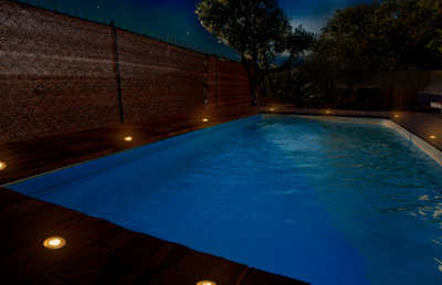 Piscine avec une terrasse bois balisée par des spots encastrés