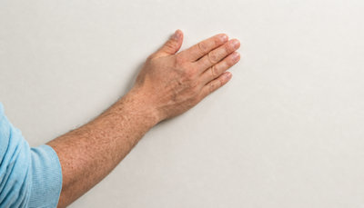 Une main passe sur le revêtement d'un mur