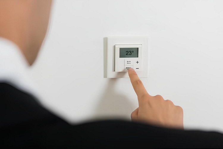 Un homme programme un thermostat