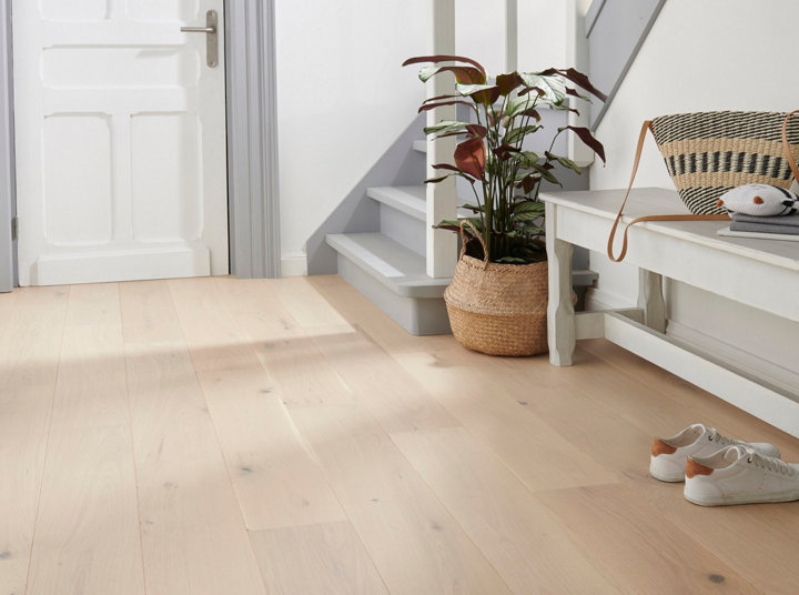 Un parquet clair dans une entrée de maison donnant sur un escalier