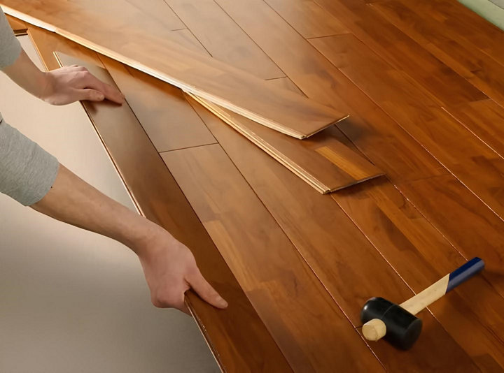 Des mains installent un parquet flottant en clipsant les lames entre elles
