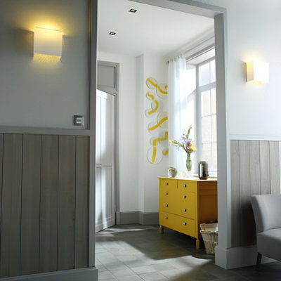 Entrée avec un meuble jaune et bas du mur sur salon avec lambris gris foncé