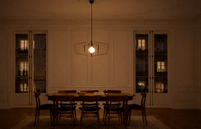 Salle à manger élégante éclairée par une suspension géométrique en métal noir. Ambiance chaleureuse et feutrée dans un style haussmannien.