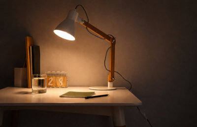 Bureau épuré avec lampe scandinave allumée, carnet, stylo, calendrier en bois et verre d'eau dans une ambiance chaleureuse.