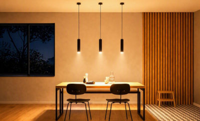 Salle à manger moderne aux tons chauds : trois suspensions noires éclairent une table en bois dans une ambiance cocooning et contemporaine.