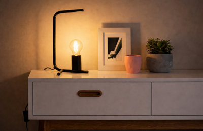 une lampe d'architecte, un cadre, des plantes sur une commode claire.