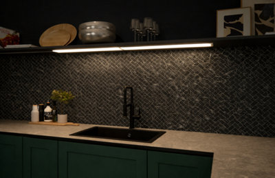 Cuisine moderne avec meuble vert, crédence sombre texturée et éclairage LED sous étagère. Idées déco et luminaires pour votre intérieur.
