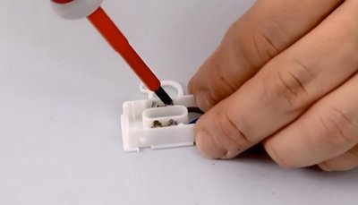 Personne qui serre avec un tourne vis les connexions.
