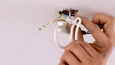 Personne qui accroche le boitier sur le crochet de fixation au plafond