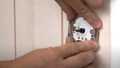 Personne qui insère le variateur dans le mur
