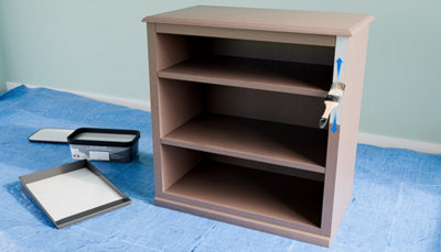 Peinture et bac avec pinceau qui peint bord meuble en bois