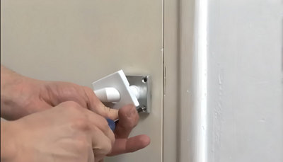 Personne qui dévisse la poignée de la porte