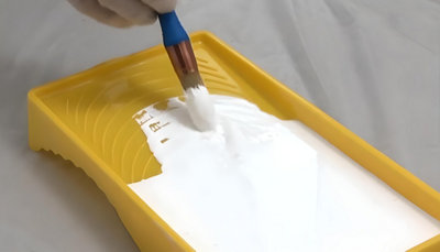 Personne qui met de la peinture blanche sur son pinceau à rechampire