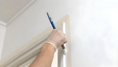 personne qui peint les contour de la porte avec pinceau rechampir