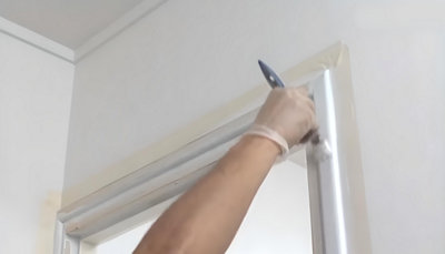 personne qui peint les contour de la porte avec pinceau plat