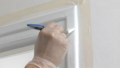 personne qui peint les contour de la porte avec pinceau plat