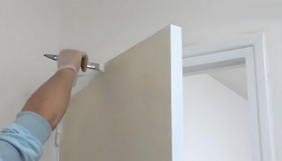 Personne qui peint le haut de la porte au pinceau